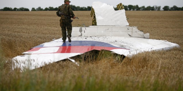 Armed pro-Russian separatist stands on part of the wreckage of the Malaysia Airlines Boeing 777 plane after it crashed near the settlement of Grabovo in the Donetsk region